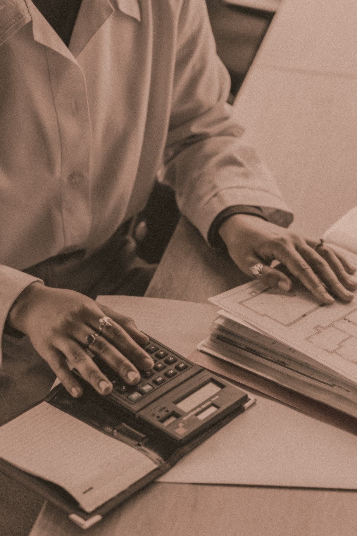 Hands working through financial paperwork beside a desk calculator