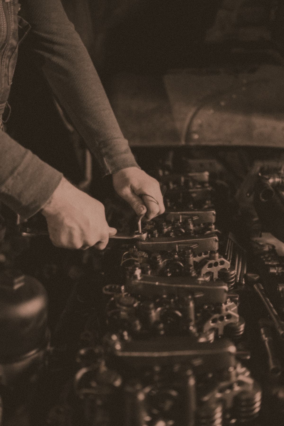 A technician tightening components on an exposed engine with a wrench