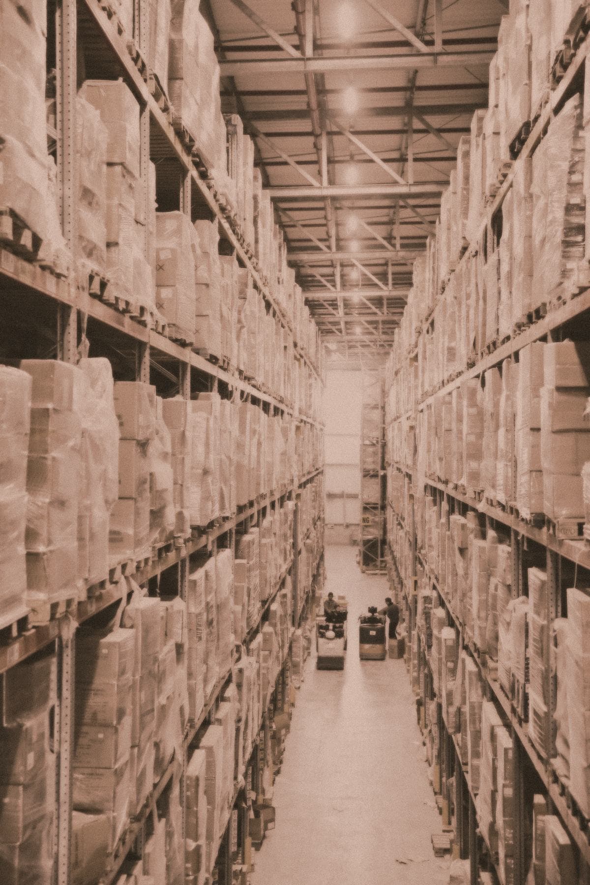 A long fulfilment-centre aisle lined with high shelving stacked with boxed stock