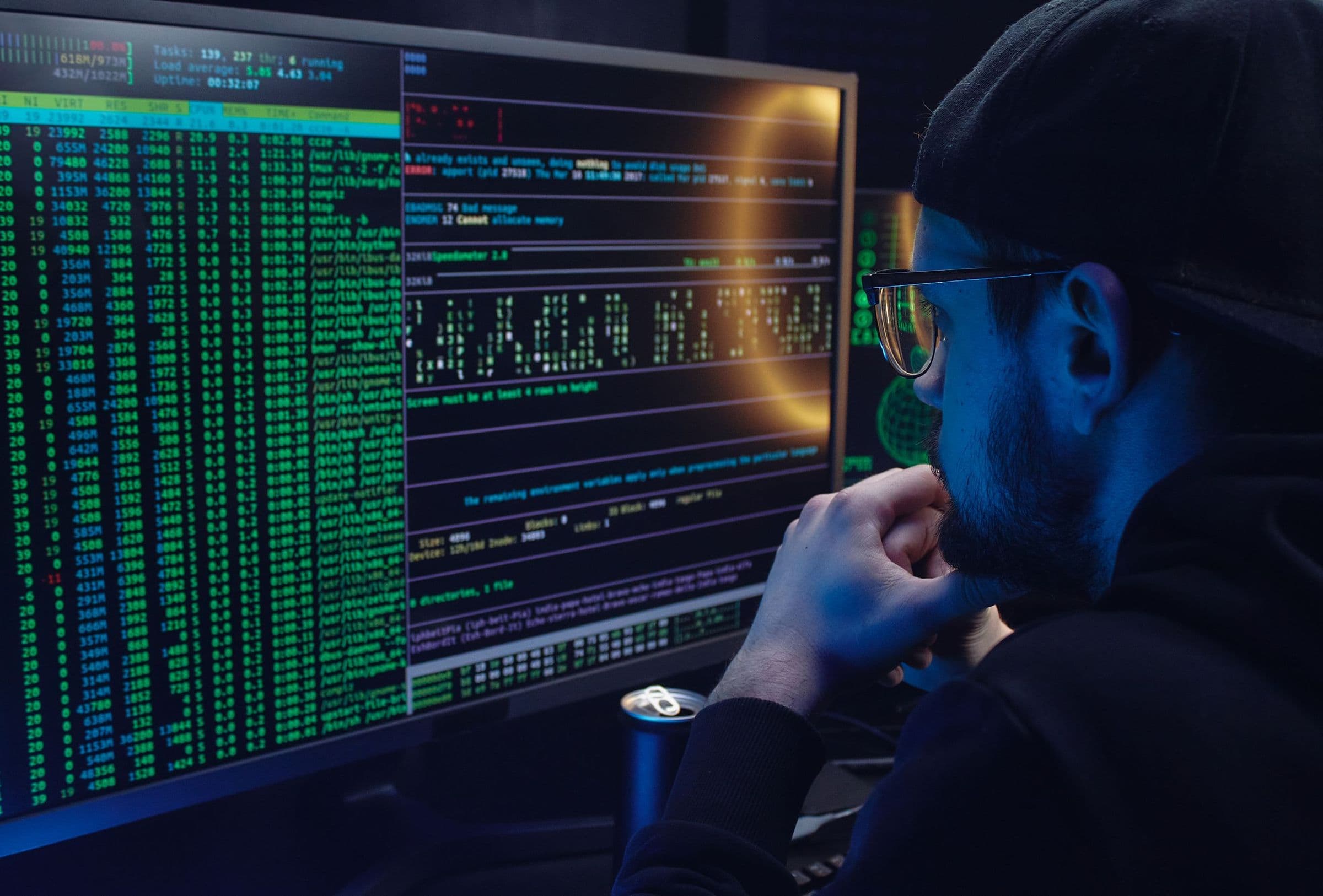 A developer studying rows of data across two monitors in a darkened room