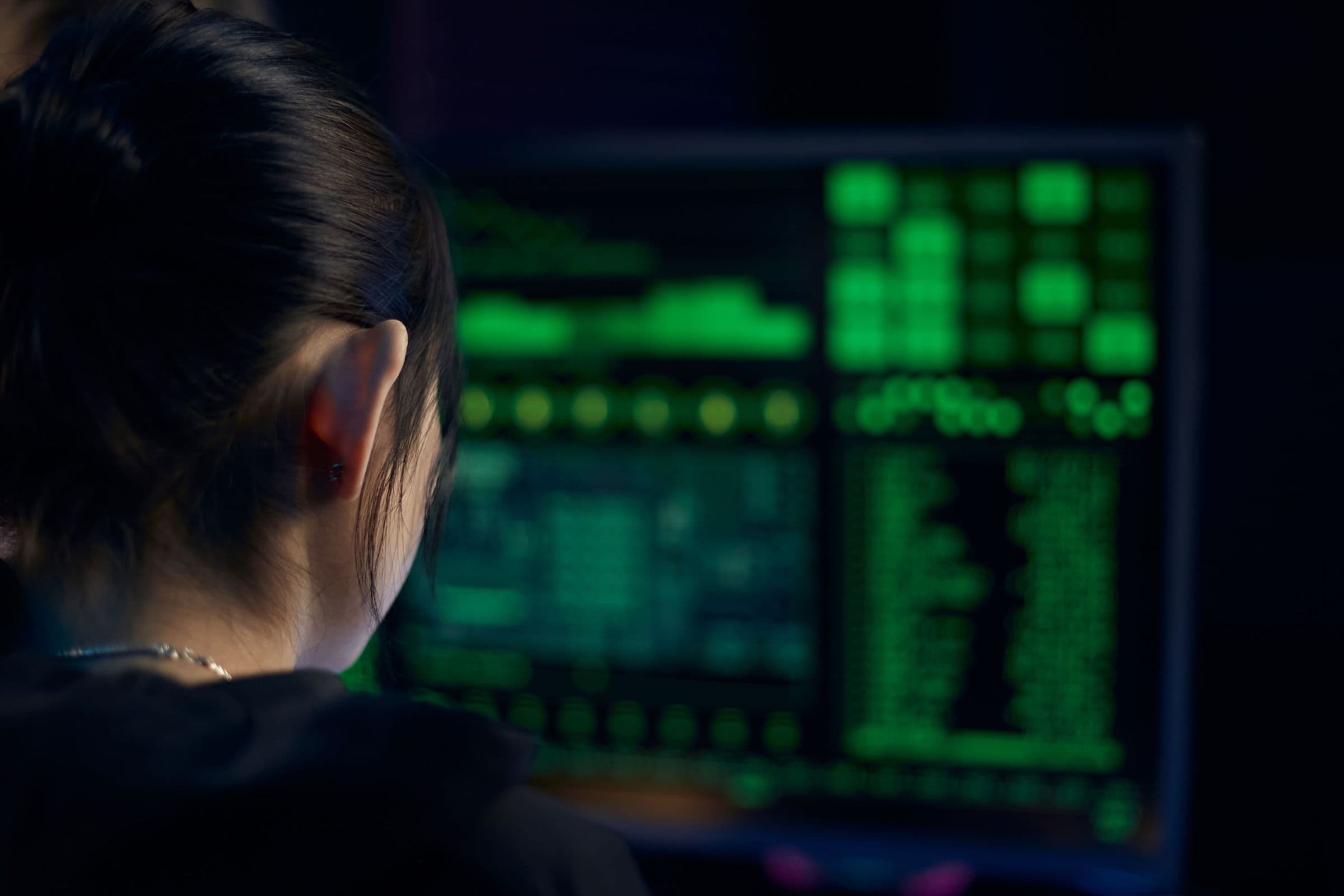 An analyst reviewing columns of data on a screen in a dim room